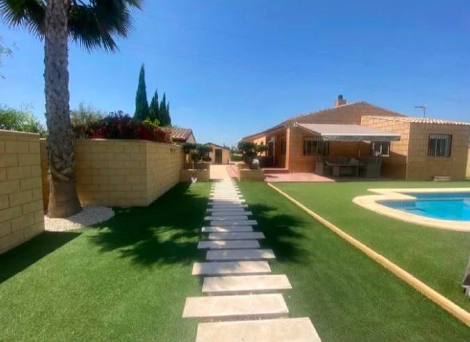 Villa garden with artificial grass, stepping stones and pool
